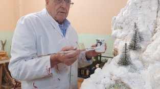 Voluntari de la gent gran, enfeinat en la decoració d'un dels elements del pessebre