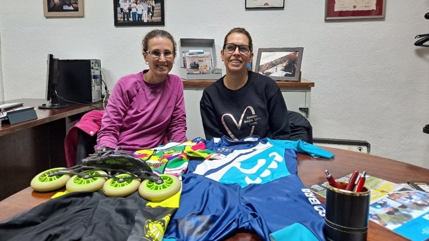 Cristina i Meritxell, en l'oficina de Delta, juntament amb els mallots de les dues entitats que pròximament s'ajuntaran