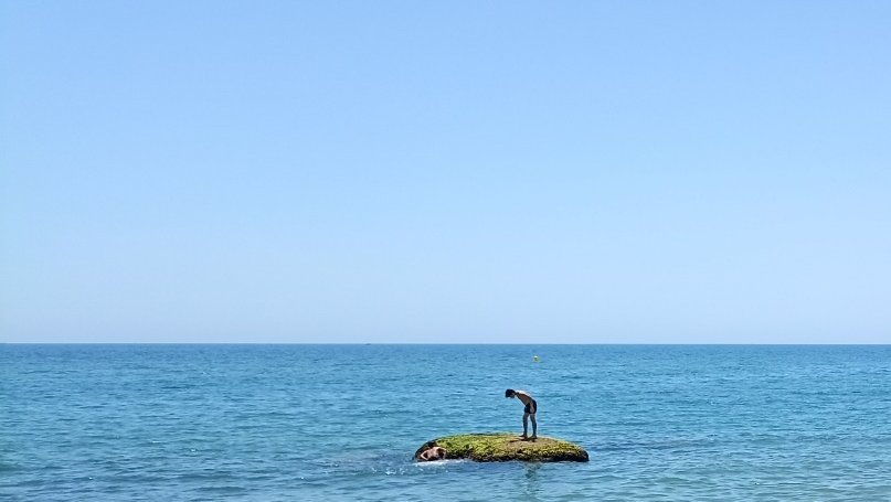 Un nen, sobre el niu de metralladora enfonsat al mar davant el Centre Municipal de Vela